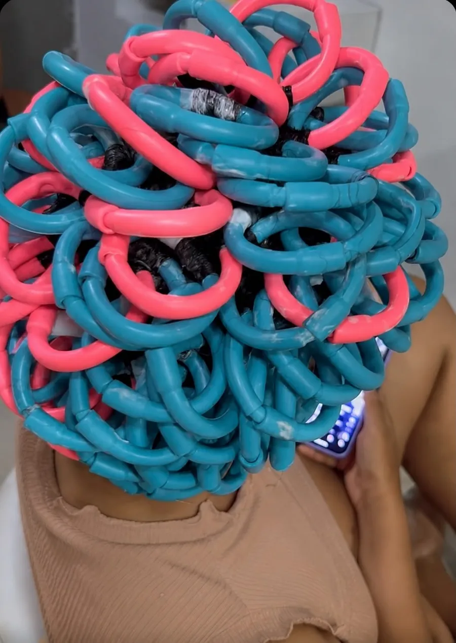 Cliente com os bobes coloridos da permanente afro durante o procedimento